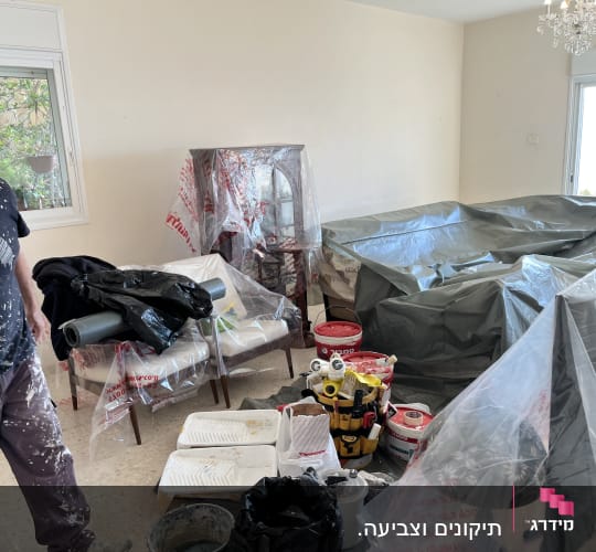 חדר עם ציוד לצביעה, פחיות צבע ומברשות